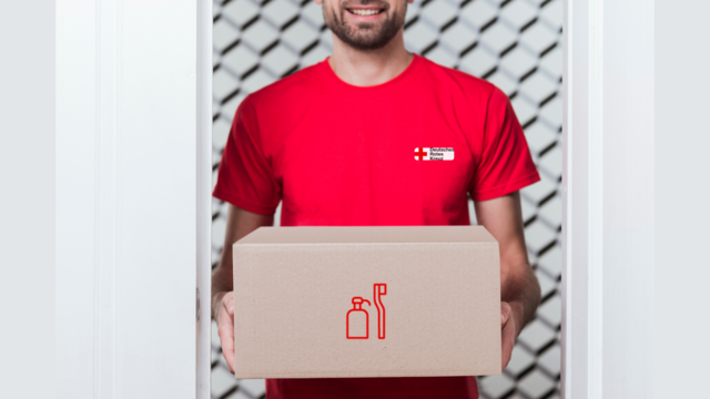 alt="Man in rotem T-Shirt hält den Pflegebox vor sich"