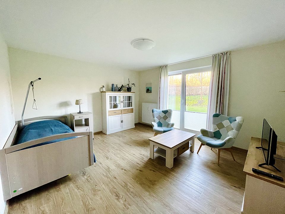 alt="Möbliertes Zimmer mit Bett, Tisch und Schrank"